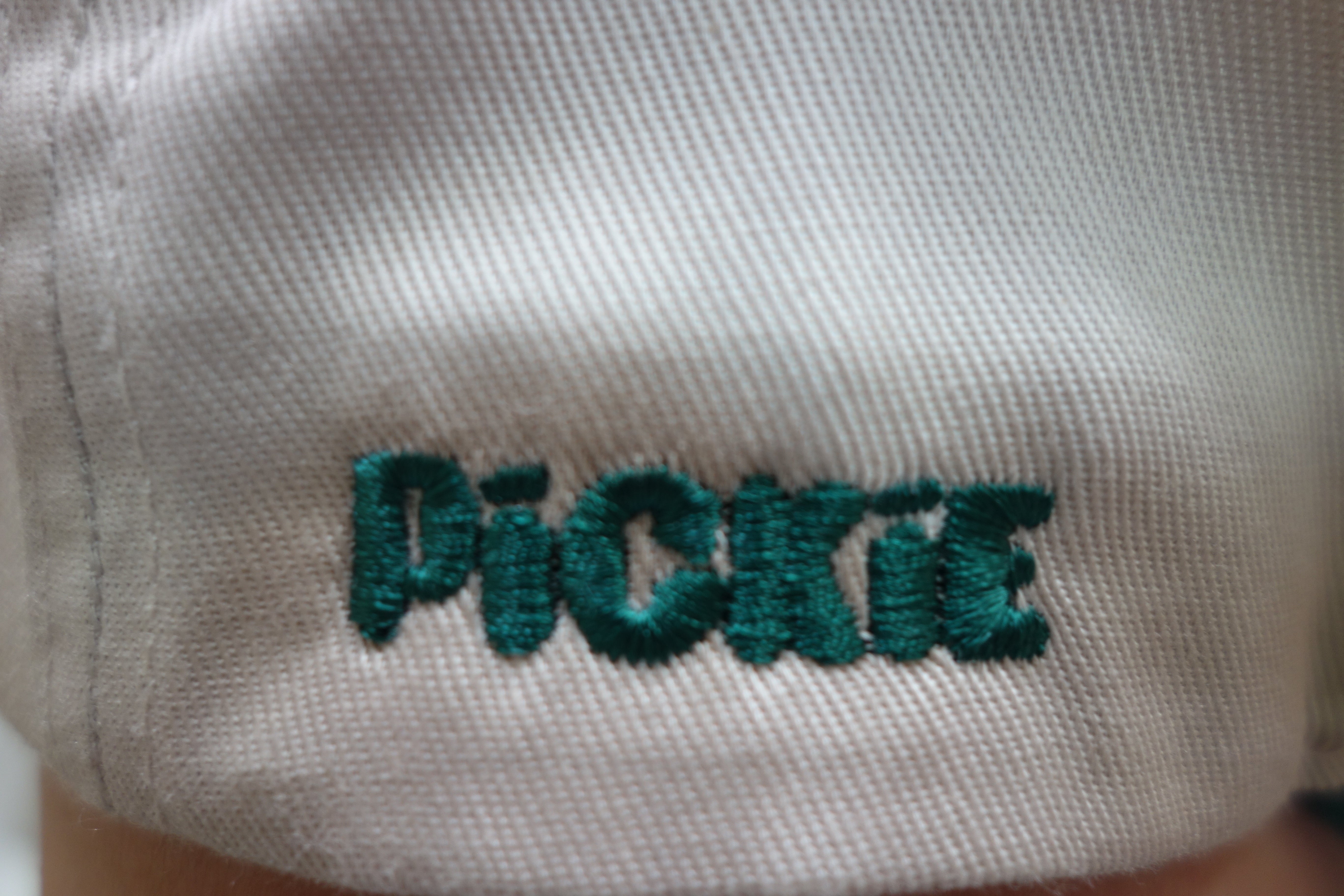 White fabric with green embroidered text on a white background