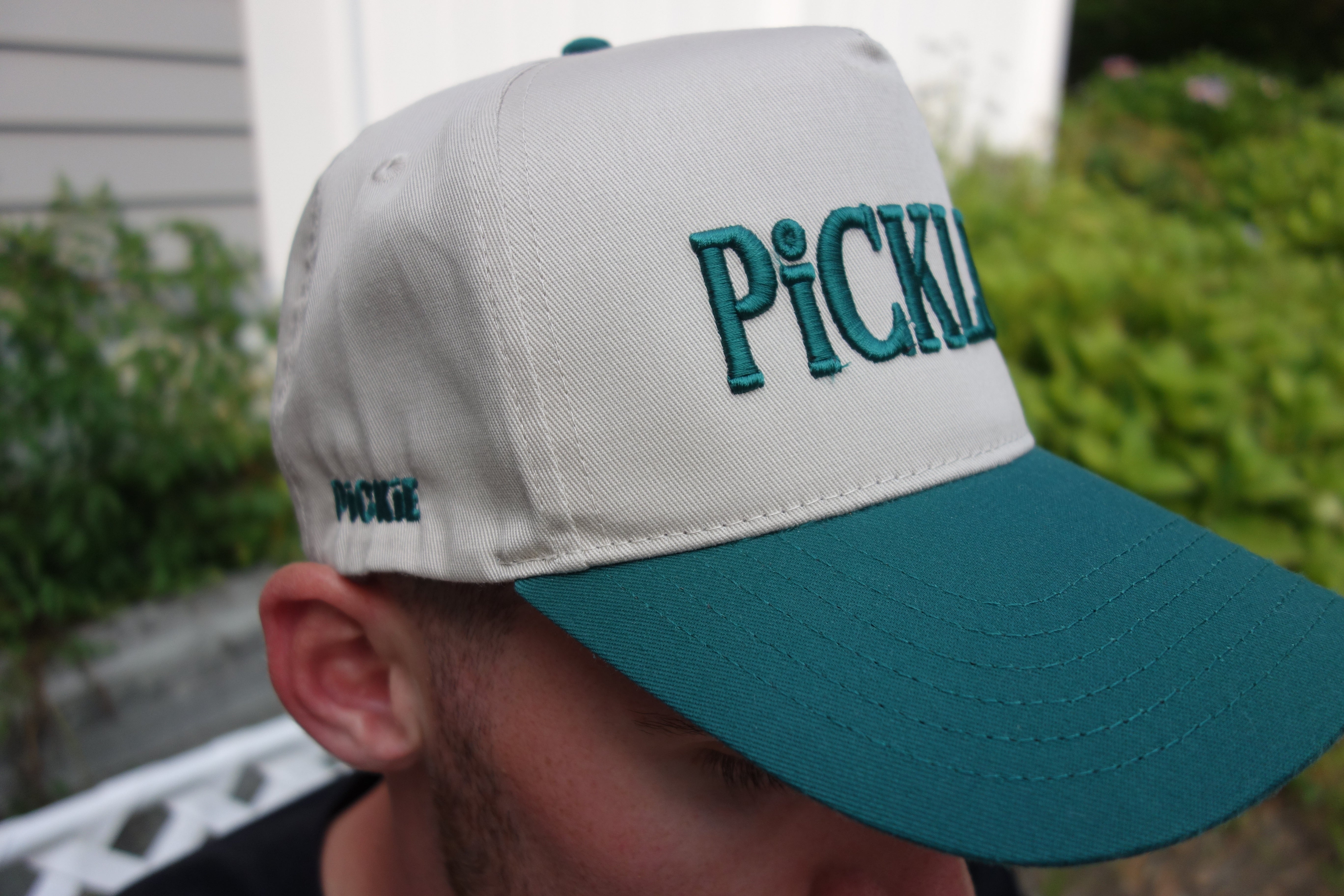 Person wearing a cap with 'PICKLE' text, blurred background